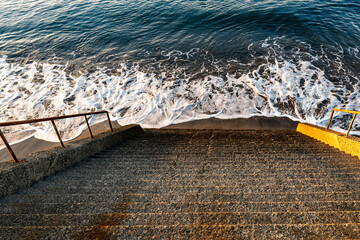 砂浜へ続く石階段と穏やかな波打ち際
