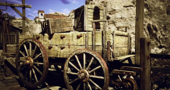 A weathered wooden cart stands still among rocky cliffs in a historic mining town, evoking a sense of nostalgia for the past. The bright sky adds to the scenes charm.