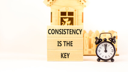 Consistency is the key symbol. Concept words Consistency is the key on beautiful wooden blocks. Beautiful white background. Black alarm clock. Business consistency is the key concept. Copy space.