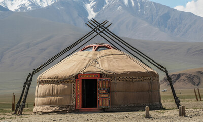 Traditional mongolian yurt dwelling located in high mountain plateau region with snow peaked peaks in background nomadic heritage