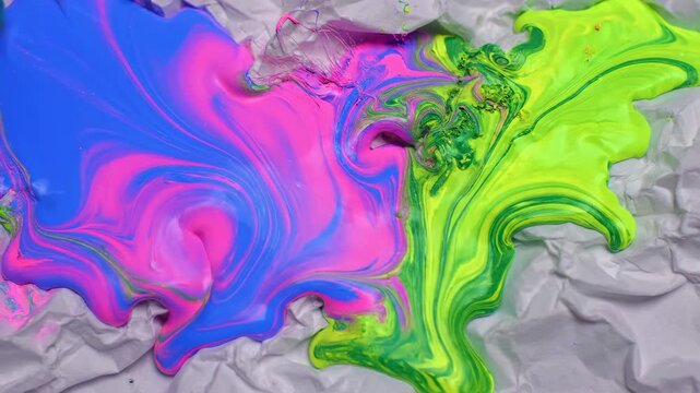 Abstract display of vibrant neon paint flowing and bleeding slowly into the deeply fibrous and highly absorbent texture of a bright crumpled paper surface macro, crumpled, slow