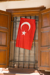 Turkish flag hanging behind a decorative iron window in a historic wooden interior.