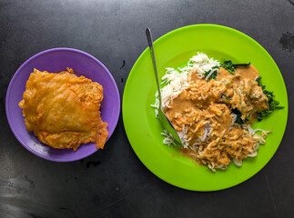 A plate of rice with peanut sauce and fried tempeh