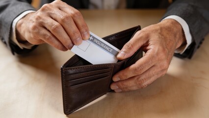 Hands placing an insurance card into a leather wallet