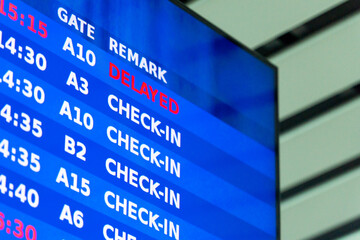 Airport departure information board showing flight status with delayed notice. Travel disruptions, wait times, airline schedule changes concept.