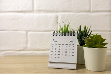 Desk calendar for March 2026 on the table, with space for text.