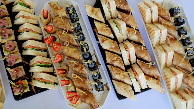Gourmet catering featuring elegant platters with colorful canapes, triangular sandwiches, and delicate rolled crepes for professional event dining