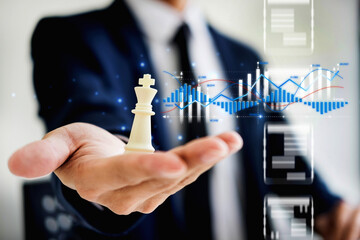 Businessman holds chess king with stock market graph hologram for strategic planning and financial investment decision symbolizes leadership success investment strategy