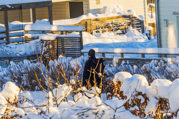 Winter view of man walking on sidewalk past villas in residential neighborhood during cold snowy weather.