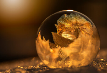 Zamrożona bańka mydlana, kryształy lodu w promieniach zachodzącego, zimowego słońca, tapeta. © mycatherina