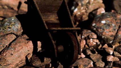 A weathered wheelbarrow stands among vibrant pebbles, illuminated by golden sunlight. The scene radiates a sense of tranquility, showing natures beauty in a quiet moment.