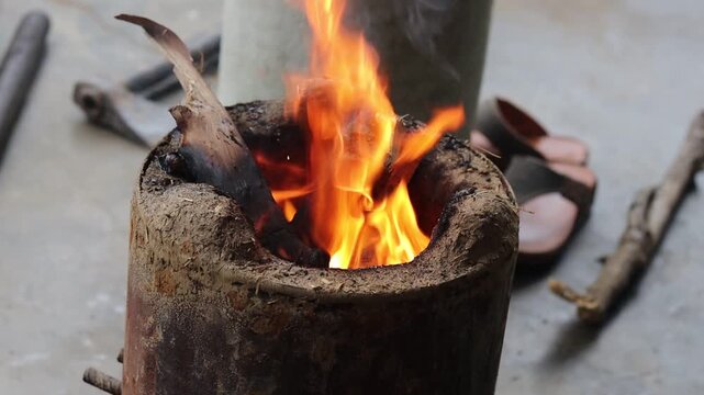 High angle close-up of wood fire burning brightly inside a traditional clay stove (Angithi) in an Indian village.