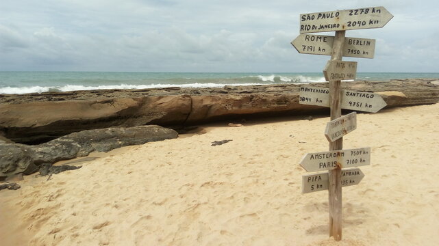 Poste con flechas que indican las distancias a otos ciudades en la playa 