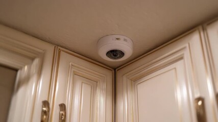 Medium shot capturing a compact heat sensor installed on a ceiling triggering automated alerts sent directly to a mobile device during a kitchen fire emergency. - Powered by Adobe