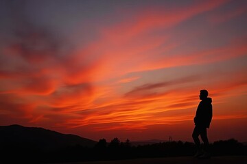 Captivating Sunset Silhouette: A stunning photo capturing a person's silhouette against a vibrant sunset backdrop, showcasing the beauty of nature and colorful outdoor scenery.