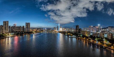 Fototapeta premium Vibrant night view of the Guangzhou city skyline and Pearl River with illuminated skyscrapers under a cloudy sky in Macau.