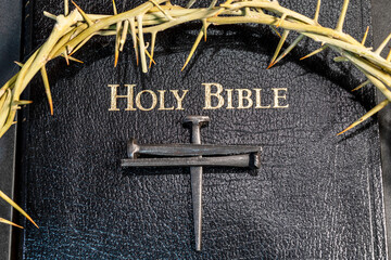 crown of thorns on black bible with rose head nail cross