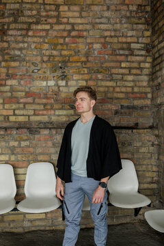 Young man waiting alone in industrial interior with brick wall