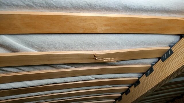 Broken cracked wooden slat on the bed under the mattress
