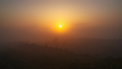 A serene landscape of a sunset over a vast, open field with a hazy sky