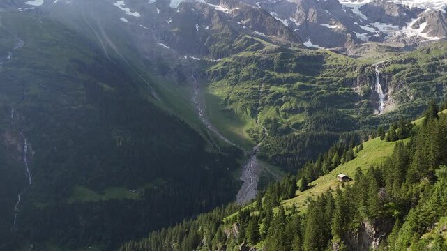 Summer drone view over the Lauterbrunnen area, capturing lush forests, towering alpine mountains, and a dramatic waterfall, revealing one of Switzerland&rsquo;s most scenic valleys