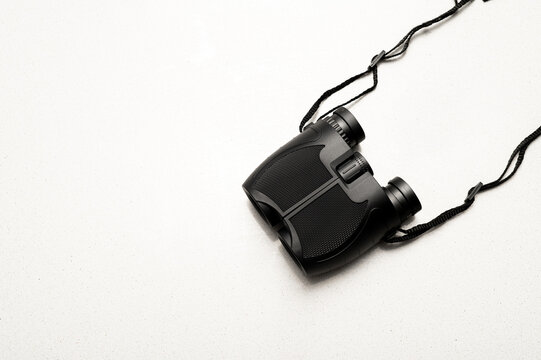 Prism&aacute;ticos negros con correa fotografiados en estudio y aislados sobre fondo blanco, mostrando su dise&ntilde;o y detalles &oacute;pticos. Concepto de observaci&oacute;n y visi&oacute;n.