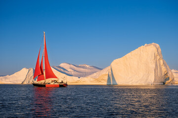 Red Sailboat Cruising Among Giant Icebergs in Disko Bay, Greenland © Michel