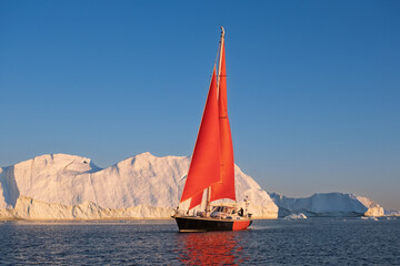 Red Sailboat Cruising Among Giant Icebergs in Disko Bay, Greenland © Michel