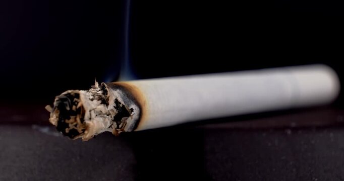 Macro Shot of Burning Cigarette with Ash and Smoke Rising on Dark Background | Health Risk Concept