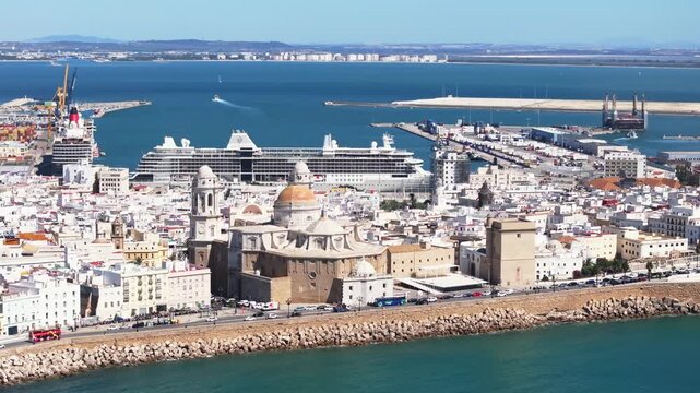 Aerial drone cityscape view of C&aacute;diz in Spain, Andalusia, Europe, on bright sunny day, facing C&aacute;diz cathedral and waterfront. Drone orbiting while panning. Commercial grading