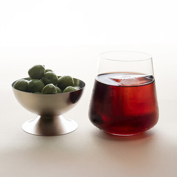 Minimalist Red Cocktail with Large Ice Cube and Olives on Light Background