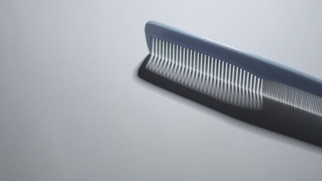 minimal still life showing a hair comb with changing elongated shadow caused by shifting background light