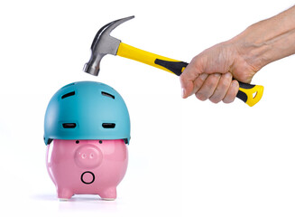Piggy bank wearing protective helmet about to be broken with hammer