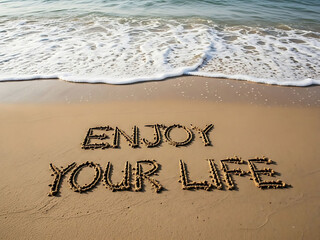 Enjoy your life message written in sand on a beach by ocean waves