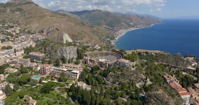 Aerial view of the theater of Taormina, in the province of Messina, Sicily, Italy. These are the ruins of an ancient Hellenistic theater from the Greek period. It is a sunny summer morning.