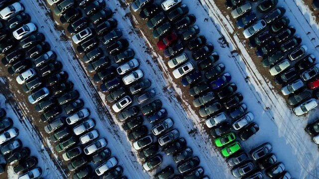 Aerial view of rows of cars parked at BCA car storage facility, a sea of metal contrasting with patches of white snow, Corby, Corby, United Kingdom.