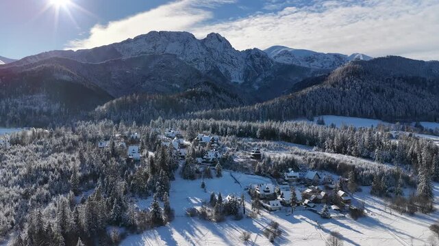 winter landscape with snow covered mountins forest and chalet houses aerial drone footage 4k