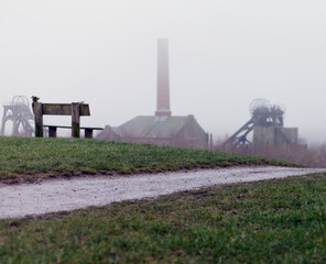 Landscape image with an old coal mine in the misty background.