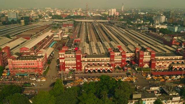 Aerial view of the Howrah Station, a historic landmark, with its red brick facade contrasting against the metallic hues of the railway tracks, Howrah, West Bengal, India.