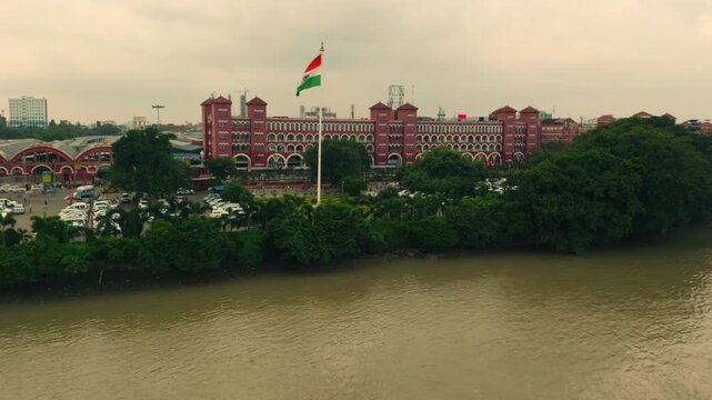 Aerial view of the historic Howrah railway station, a majestic red brick building, with the Indian flag waving, Howrah, West Bengal, India.