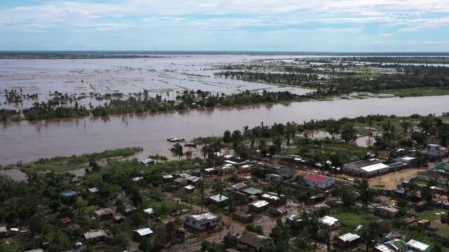 Aerial view of a river overflowing its banks, submerging homes and fields in muddy waters, creating a scene of devastation, Beira, Sofala Province, Mozambique.