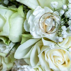 Obraz premium Close up of golden wedding rings lying on white rose petals. Soft romantic lighting highlights love, unity and commitment. Perfect symbol of marriage and engagement.