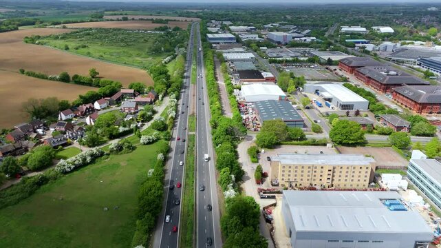 Aerial view of the A1(M) motorway stretching through the landscape, flanked by industrial buildings and green spaces, Stevenage, England, United Kingdom.
