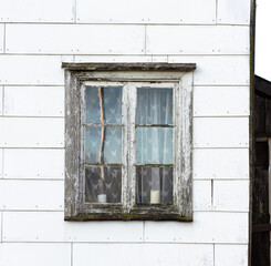 Weathered wooden window on white house exterior.