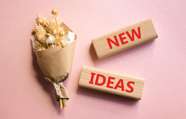 New ideas symbol. Concept word New ideas on wooden blocks. Beautiful pink background with bouquet of flowers. Business and New ideas concept. Copy space