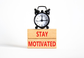 Motivation symbol. Concept words Stay Motivated on wooden blocks. Beautiful white background with alarm clock. Business and Stay Motivated concept. Copy space