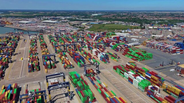 Aerial view of vibrant shipping containers stacked in neat rows at the bustling port, creating a colorful tableau against the backdrop, Felixstowe, United Kingdom.