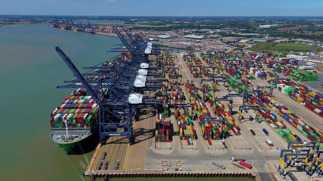 Aerial view of a large container ship docked at Port of Felixstowe, surrounded by stacks of colorful containers and towering cranes, Felixstowe, Felixstowe, United Kingdom.
