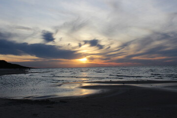 Obraz premium Sunset over the Baltic Sea on the Polish coast, calm sea and dramatic sky during golden hour.