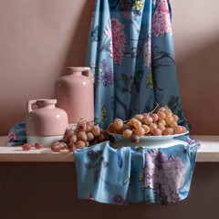 Still life with soft pink jugs, pink and blue satin fabric and pink grapes